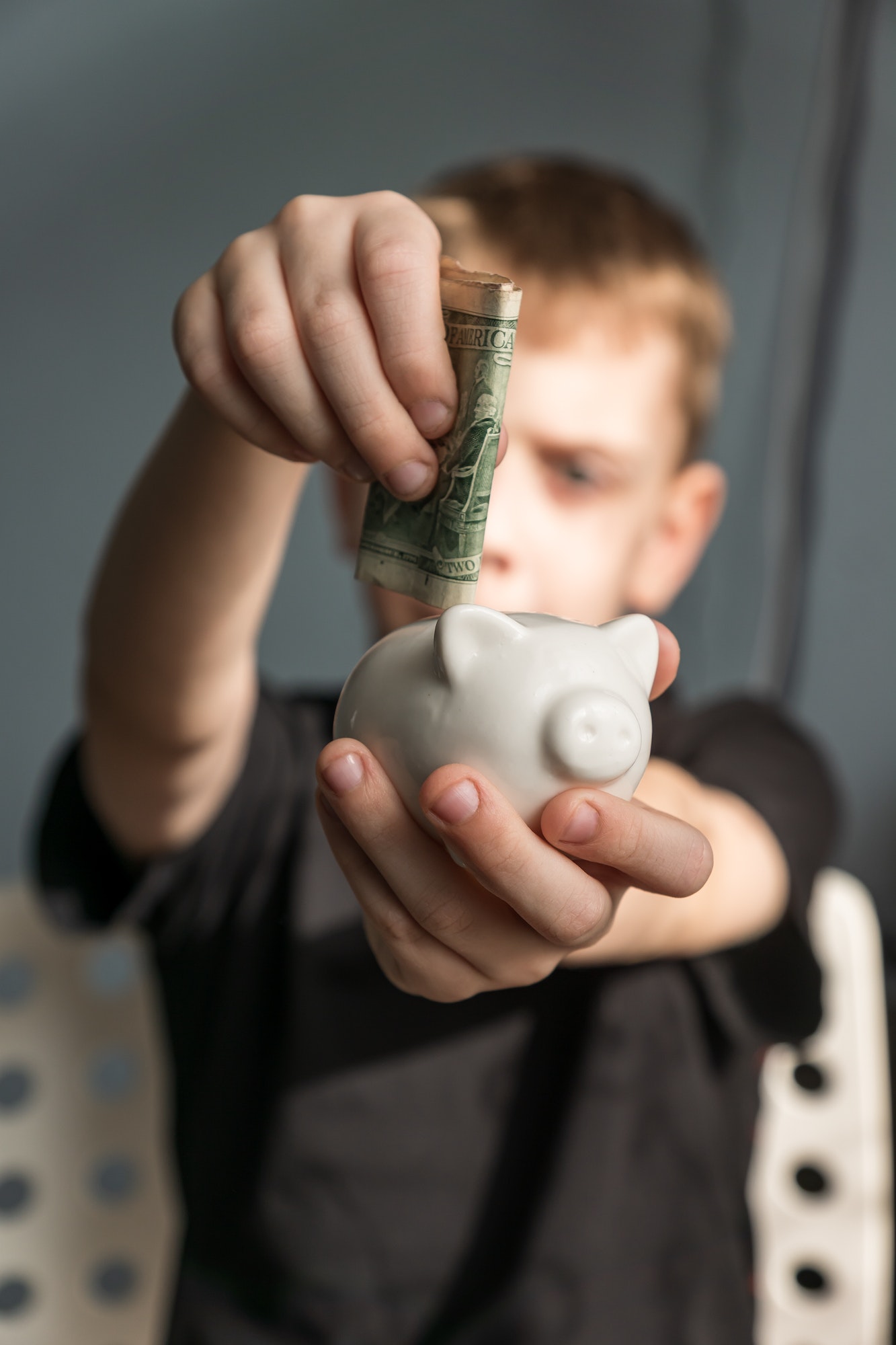 little kid investor putting his first us dollar into piggy bank